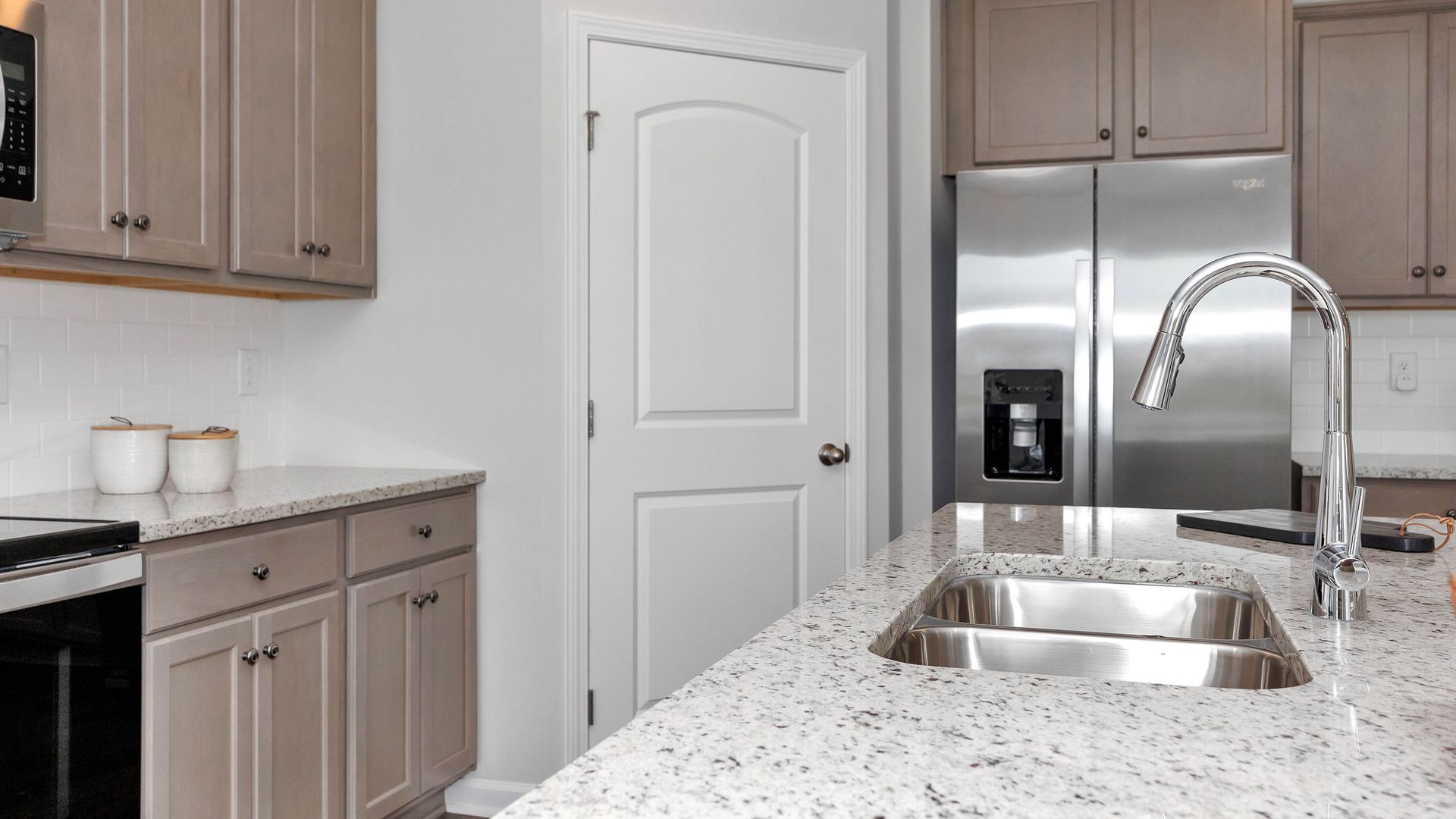 Kitchen with granite countertops, stainless steel sink and appliances, and beige cabinets.