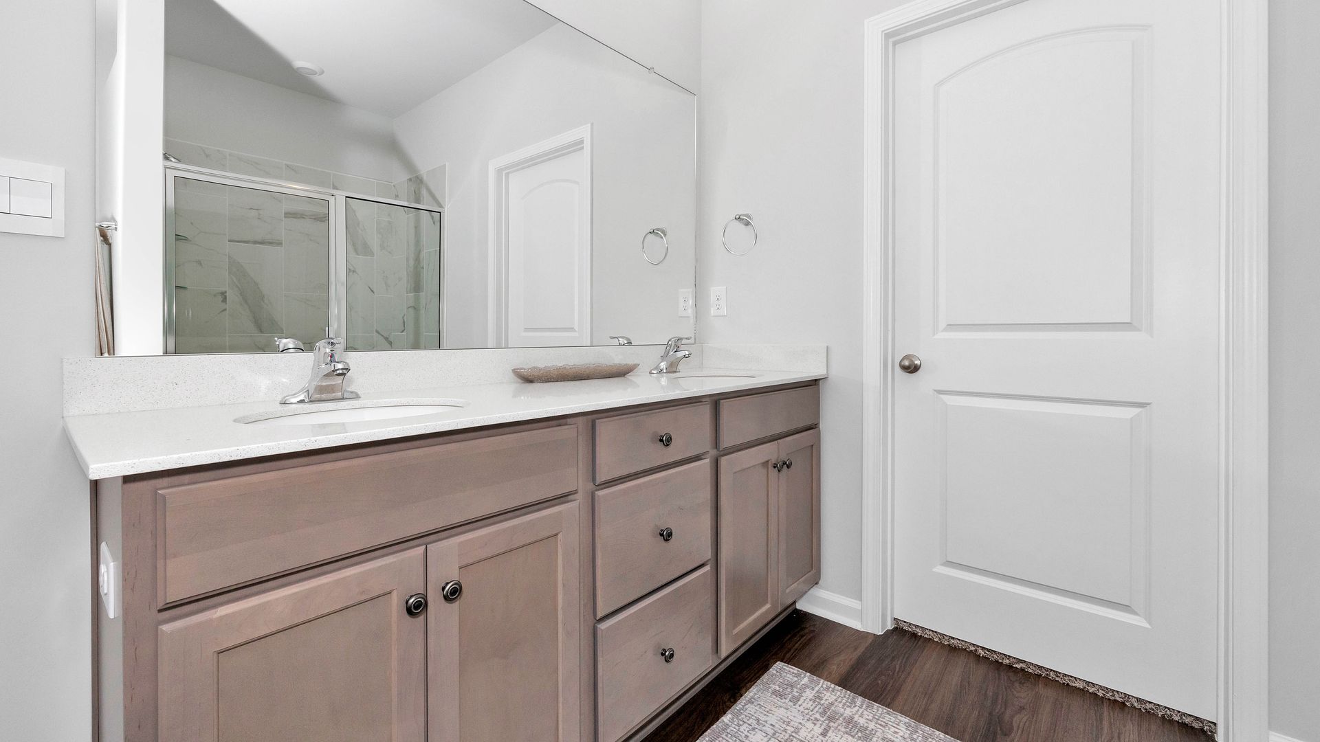 Bathroom with double vanity, gray cabinets, white countertop, and a white door.