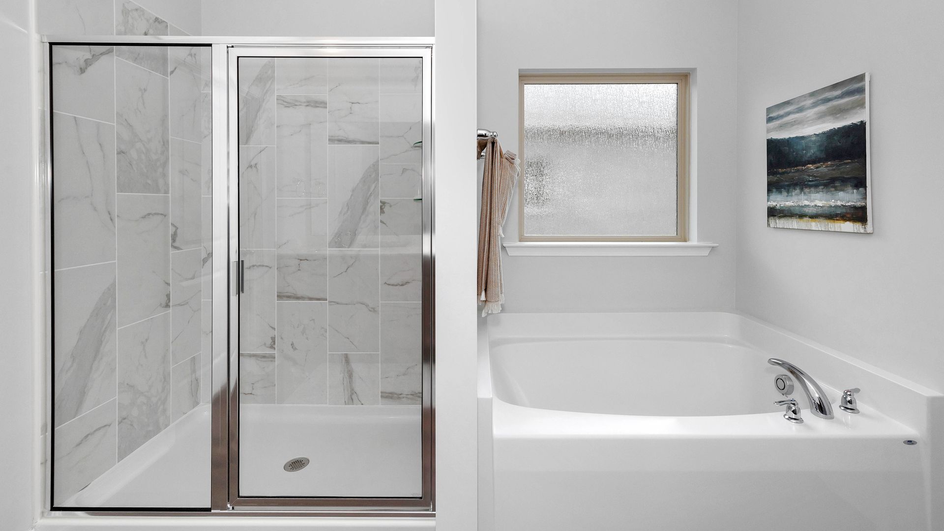 Bathroom with a white bathtub, shower with glass door, and marble tiles. There's a frosted window and artwork on the wall.