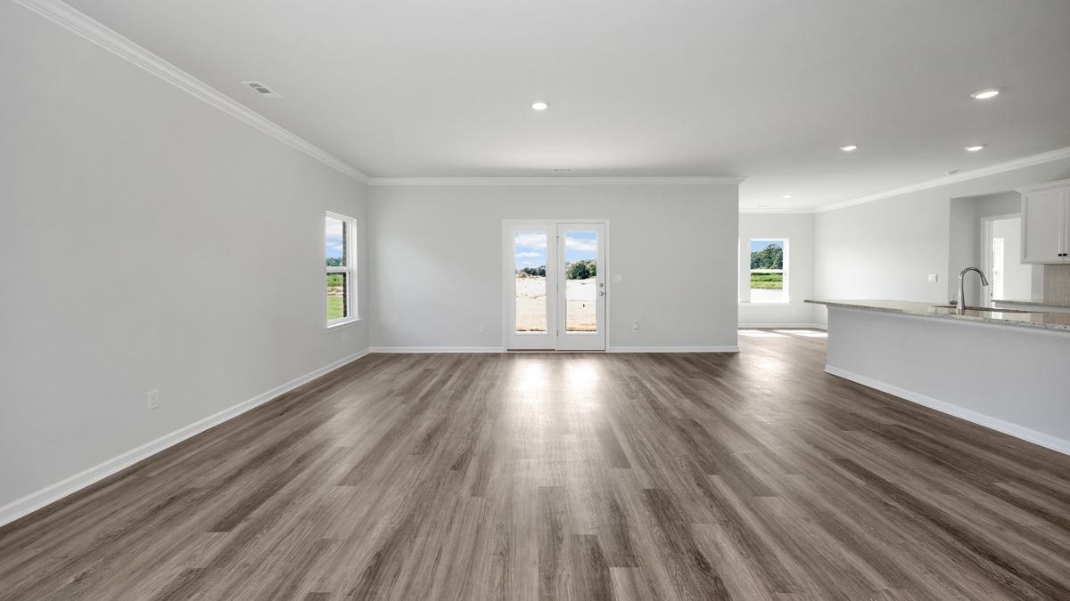 Empty living room with wood flooring, white walls and trim, and French doors.
