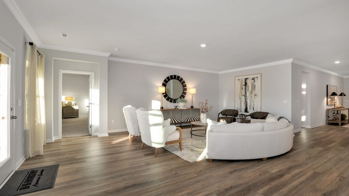 Spacious living room with white furniture, grey walls, wood floors, and natural light.