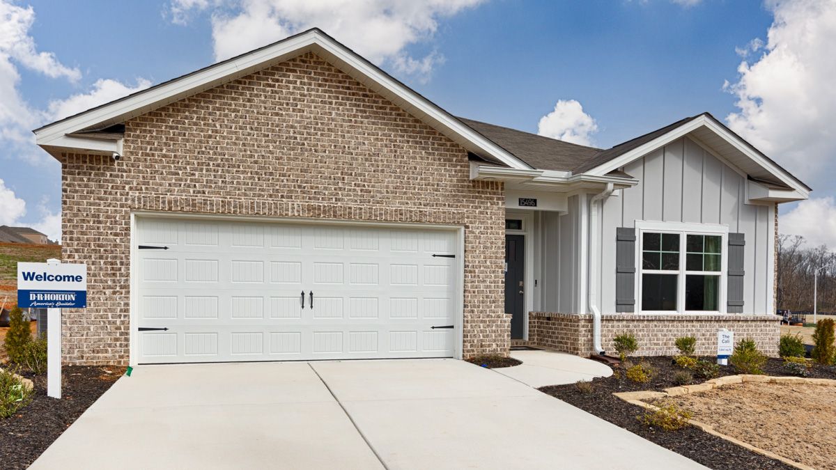 A modern, brick and white home with a two-car garage on a sunny day.