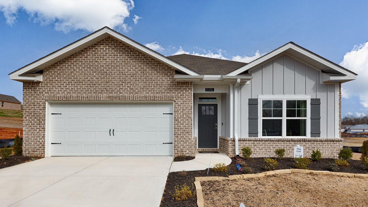 Ranch-style house with brick and gray siding, white garage door, blue sky.