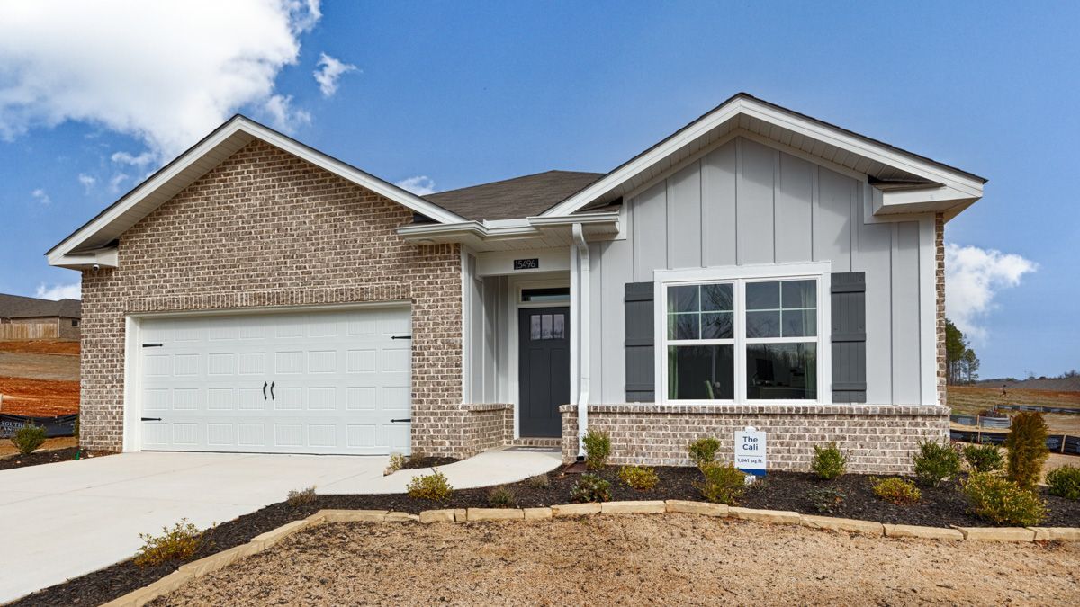 A one-story house with a brick and gray exterior, garage, and blue sky.