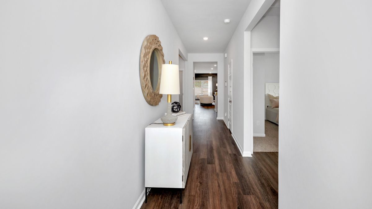 Hallway with white walls, dark wood floor, console table, and mirror.