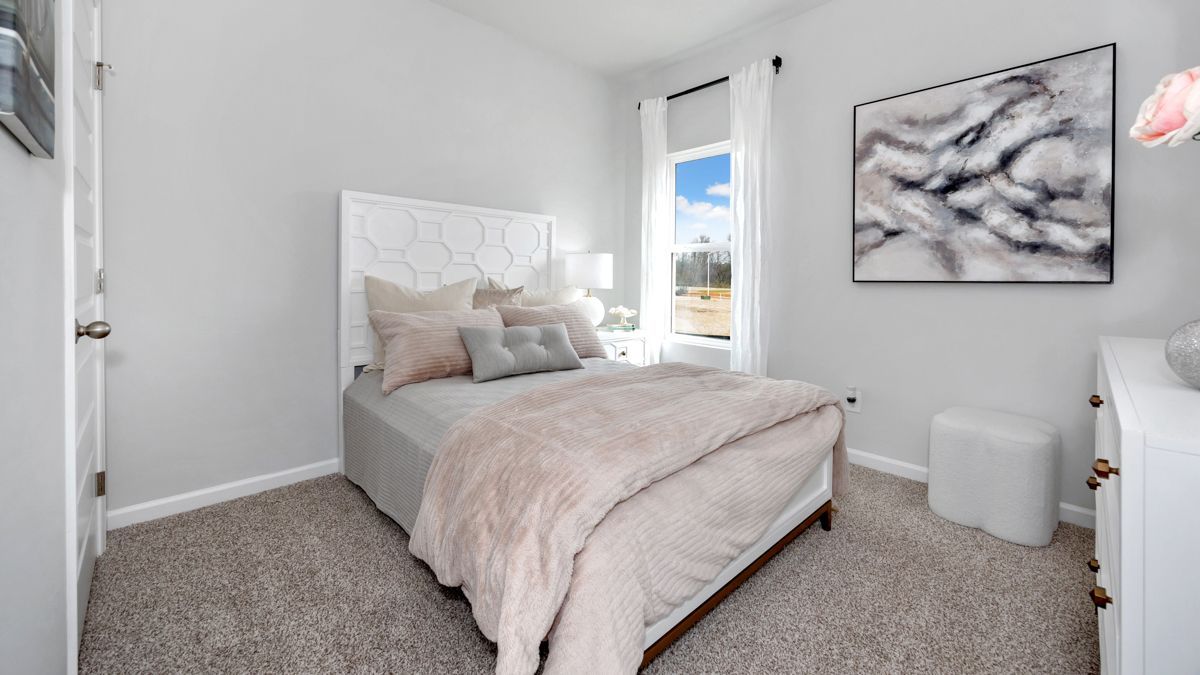 Bedroom with a bed, gray walls, artwork, and a window overlooking a landscape.