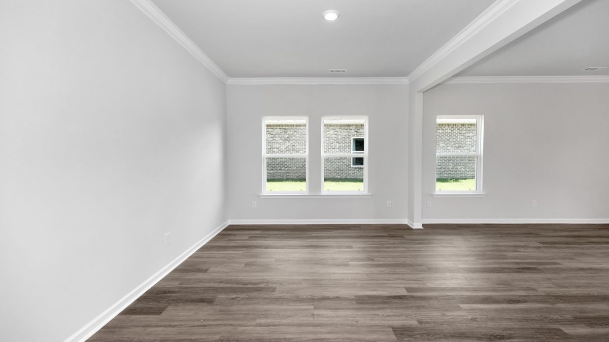Empty room with wood floor, white walls, three windows, and a beam.
