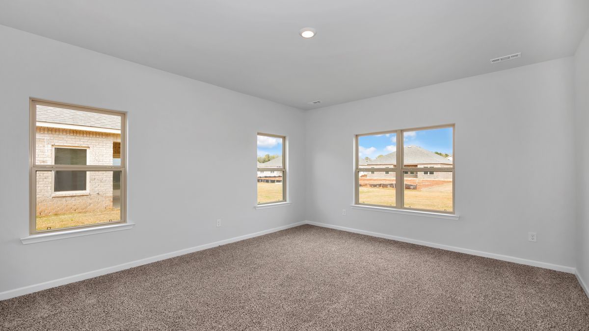 Empty room with three windows and tan carpet; white walls and ceiling.