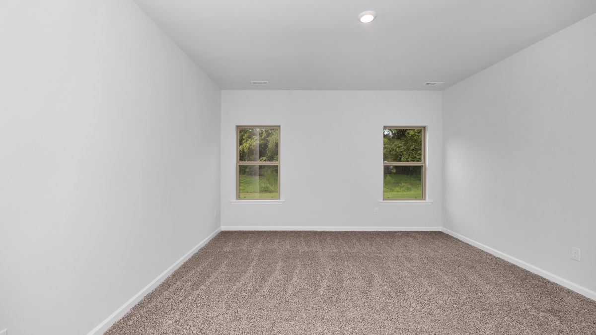 Empty room with beige carpet, white walls, and two windows with outside view.