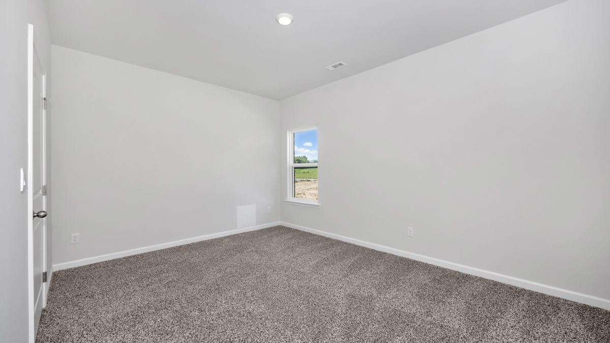 Empty room with gray carpet, white walls, window showing an outdoor view.