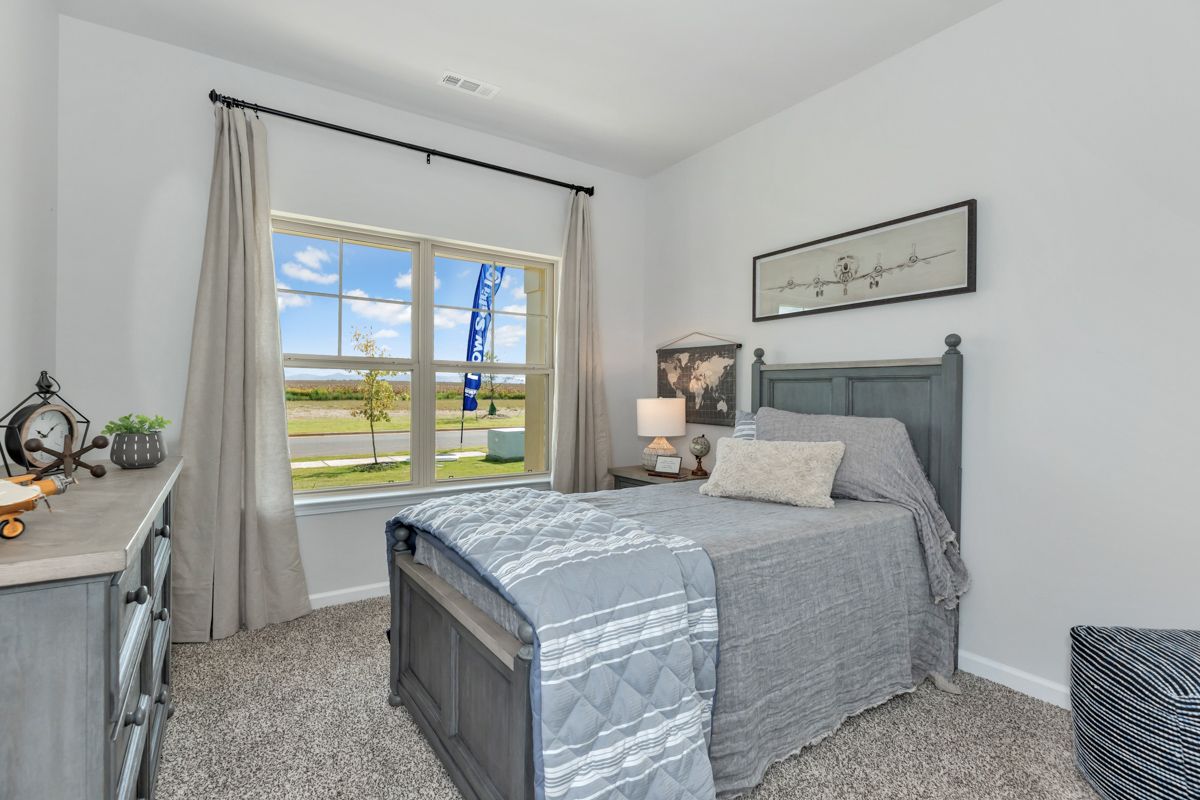 Bedroom with a gray bed, dresser, window, and gray curtains.