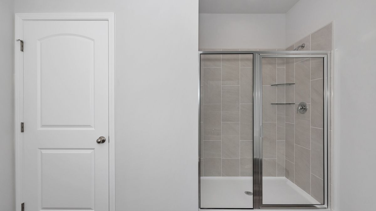 White door and shower with sliding glass doors in a bathroom.