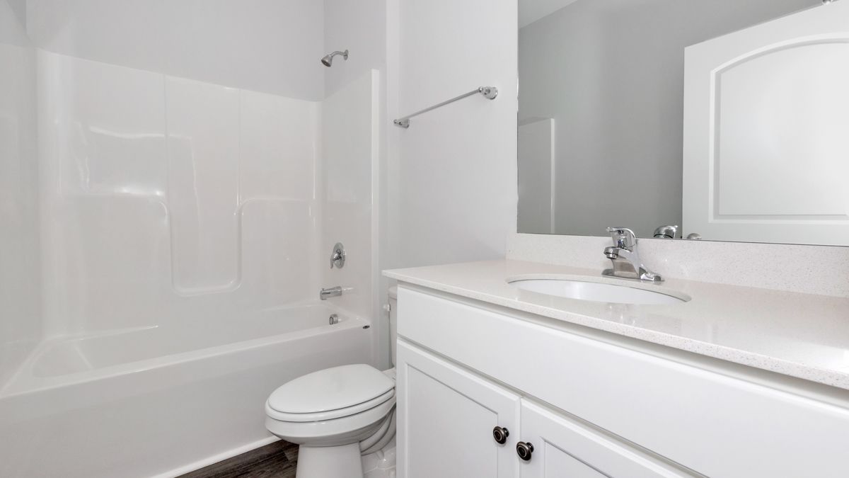 White bathroom with a tub, toilet, sink, and cabinet.