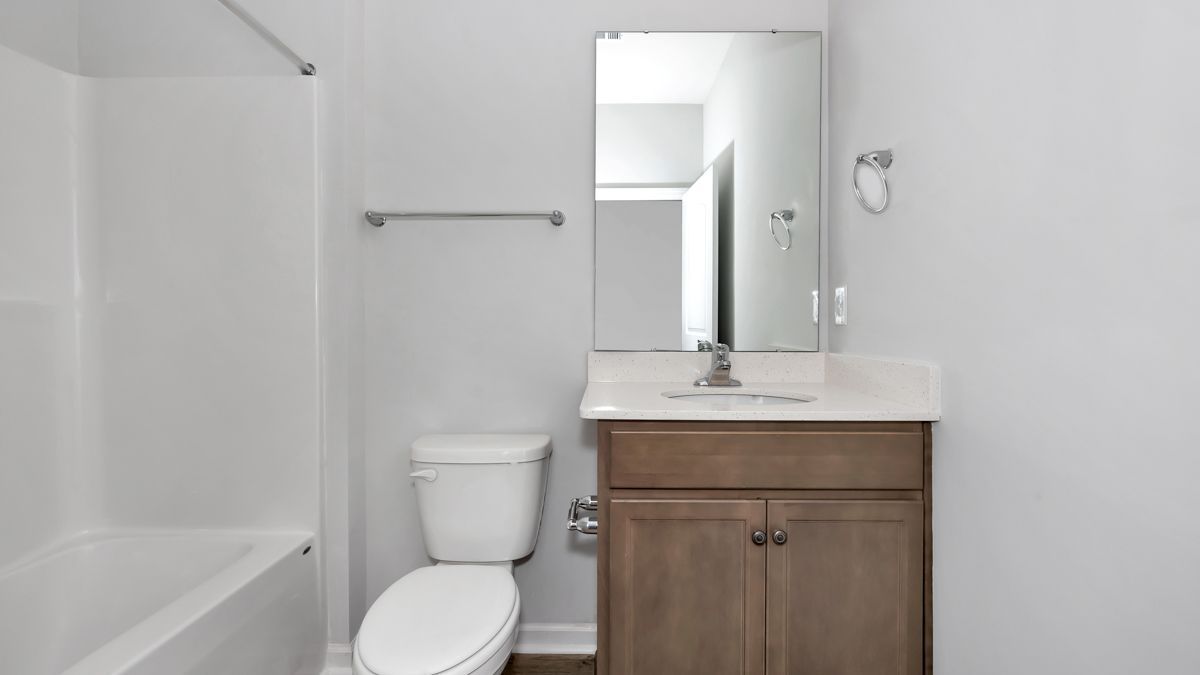 Small bathroom with a white tub, toilet, vanity, and gray walls.