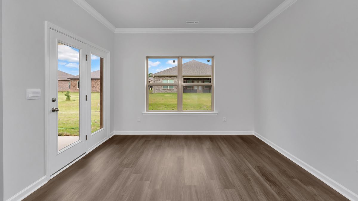 Empty room with gray walls, wood floor, and two doors and a window with a view of the outdoors.