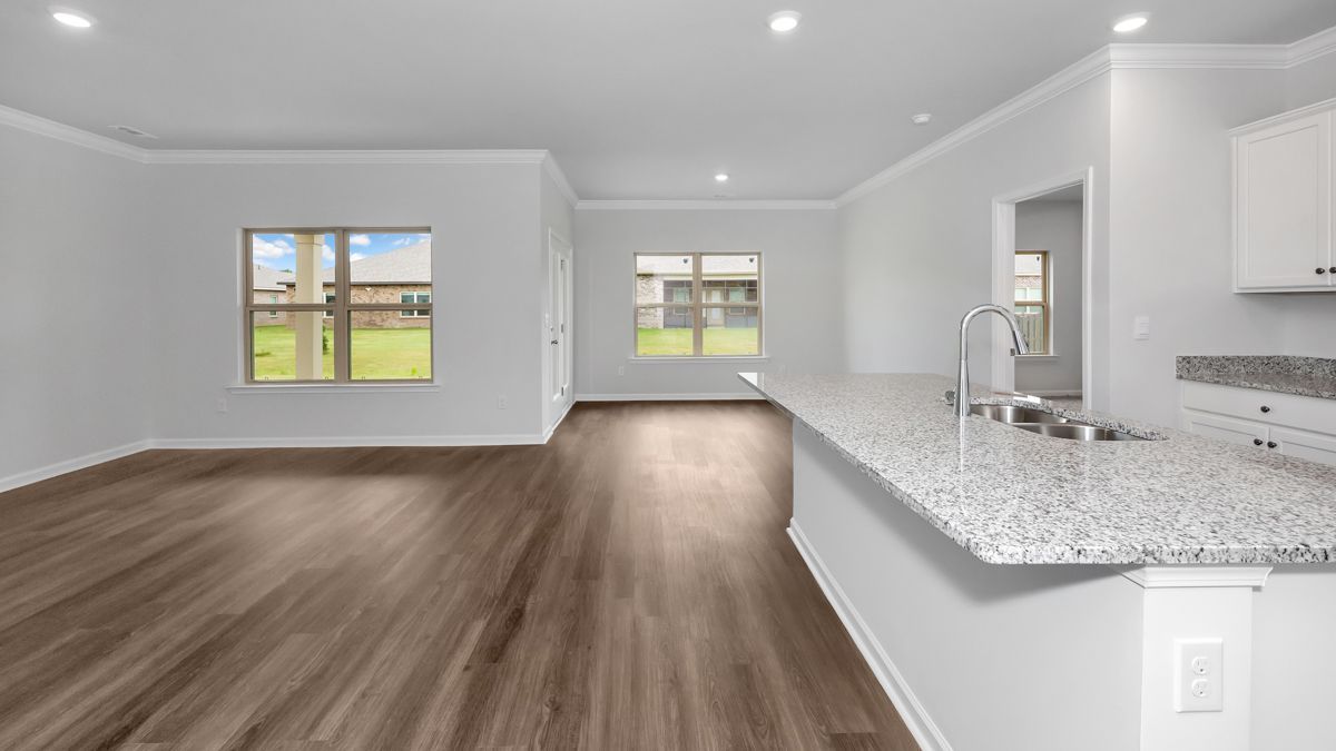 Spacious, bright living room with wood floors, two windows, and a kitchen with granite countertops.