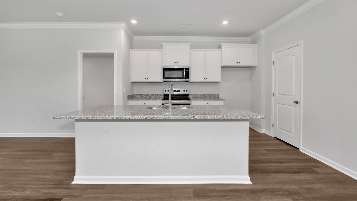White kitchen with island, granite countertop, stainless steel appliances, and hardwood floors.