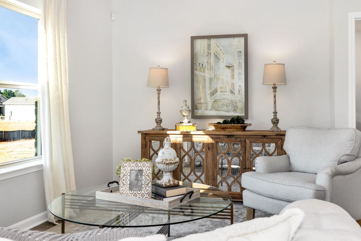 Living room with neutral colors, wood console table, armchair, and decor.