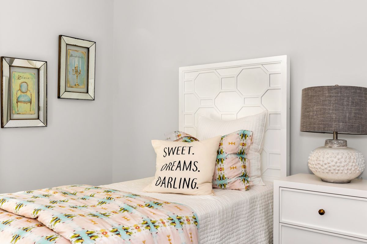 Bedroom with a white bed, nightstand, and headboard. Soft bedding, 