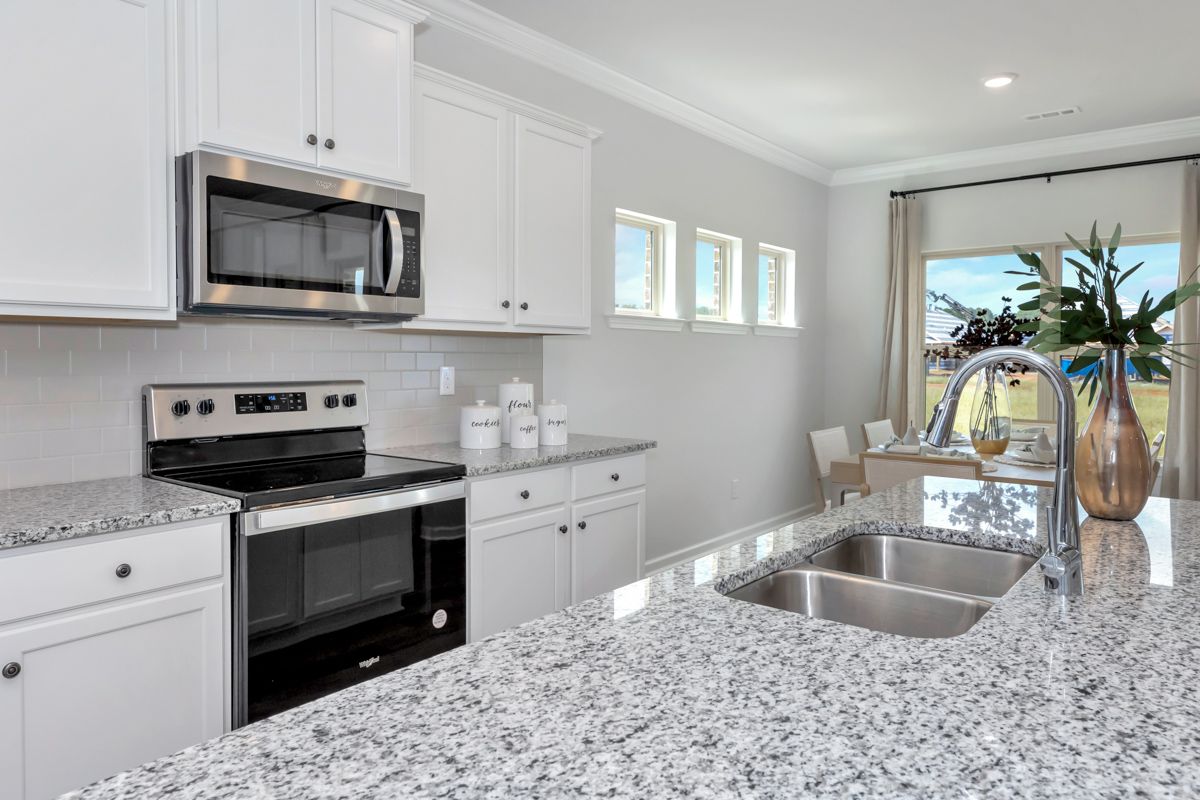 White kitchen with granite countertops, stainless steel appliances, and a window.