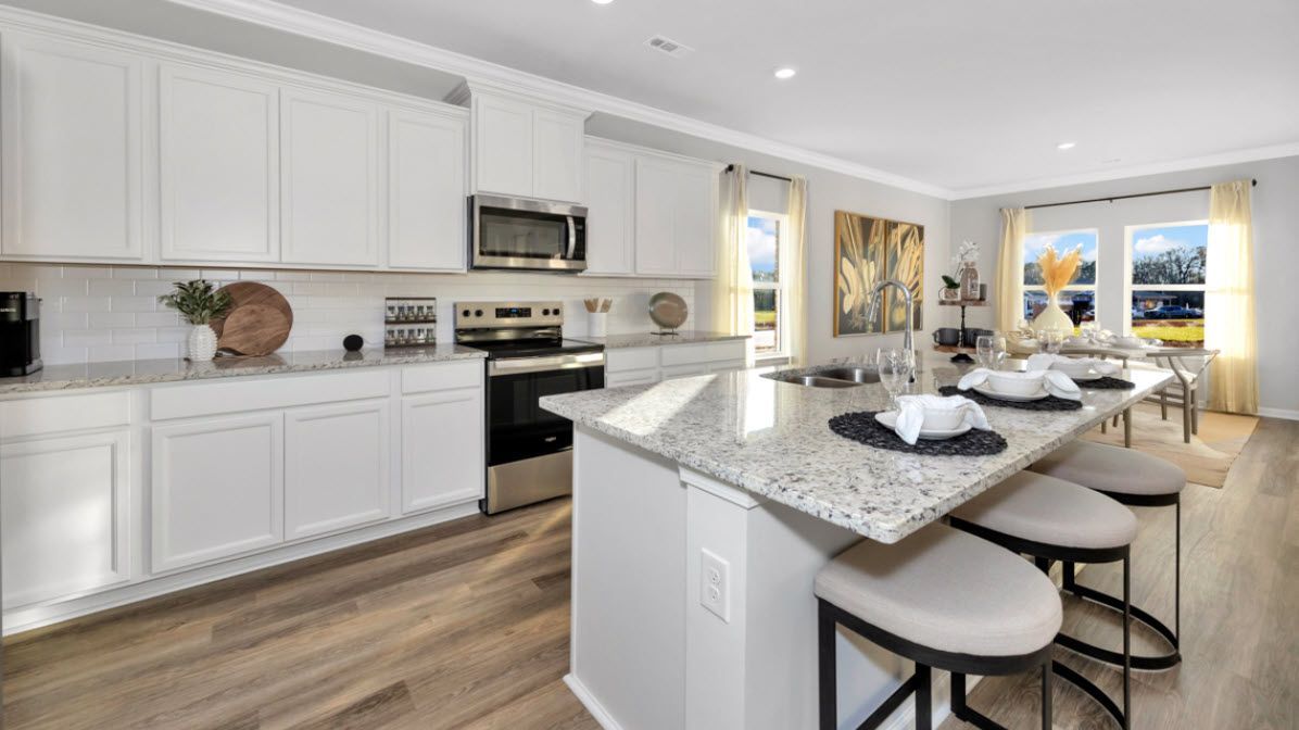 Modern kitchen with white cabinets, granite counters, and a large island with seating.