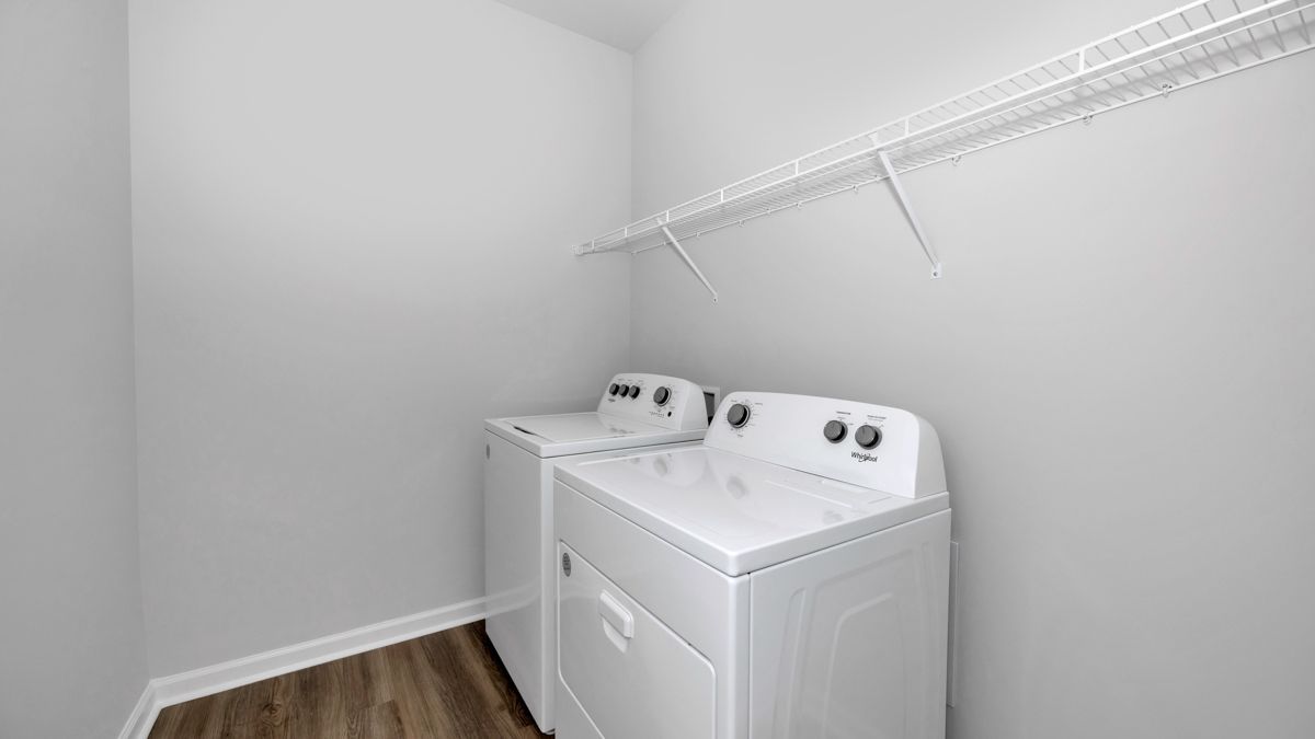 A white washer and dryer in a laundry room with a shelf above.