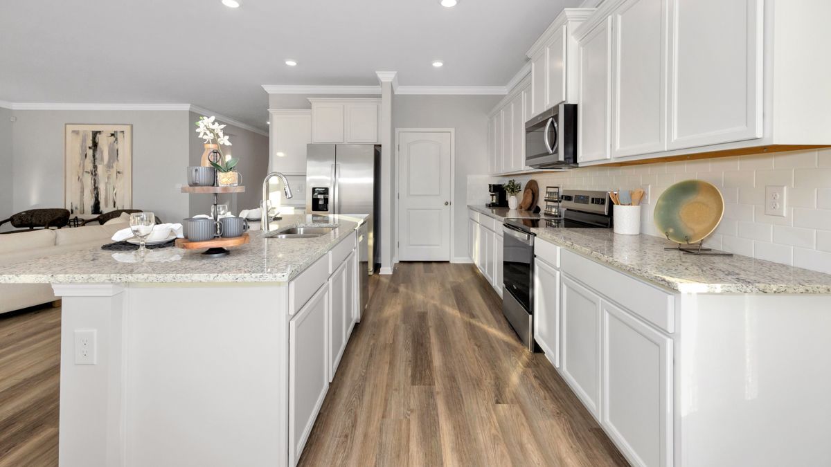 Bright white kitchen with granite countertops, stainless steel appliances, and wood flooring.