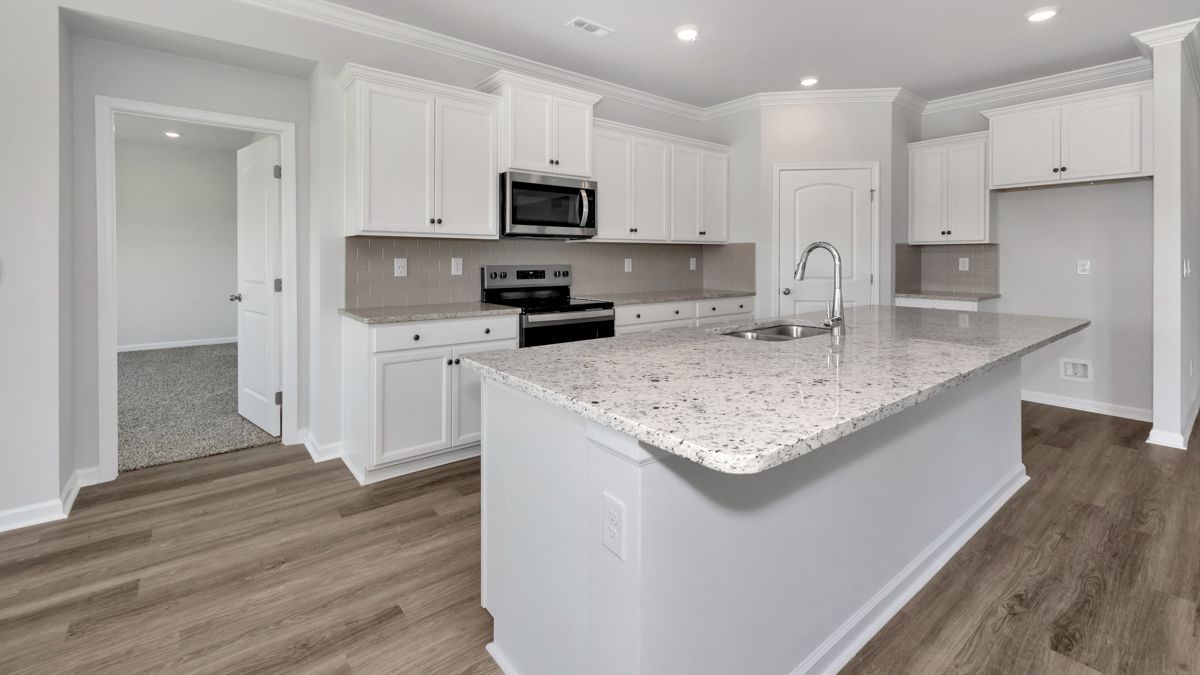 Modern white kitchen with island, granite countertops, and stainless steel appliances.