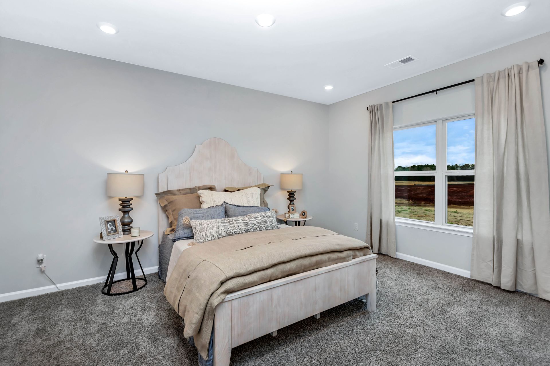 Bedroom with bed, two nightstands, window with curtains, gray walls, carpet.