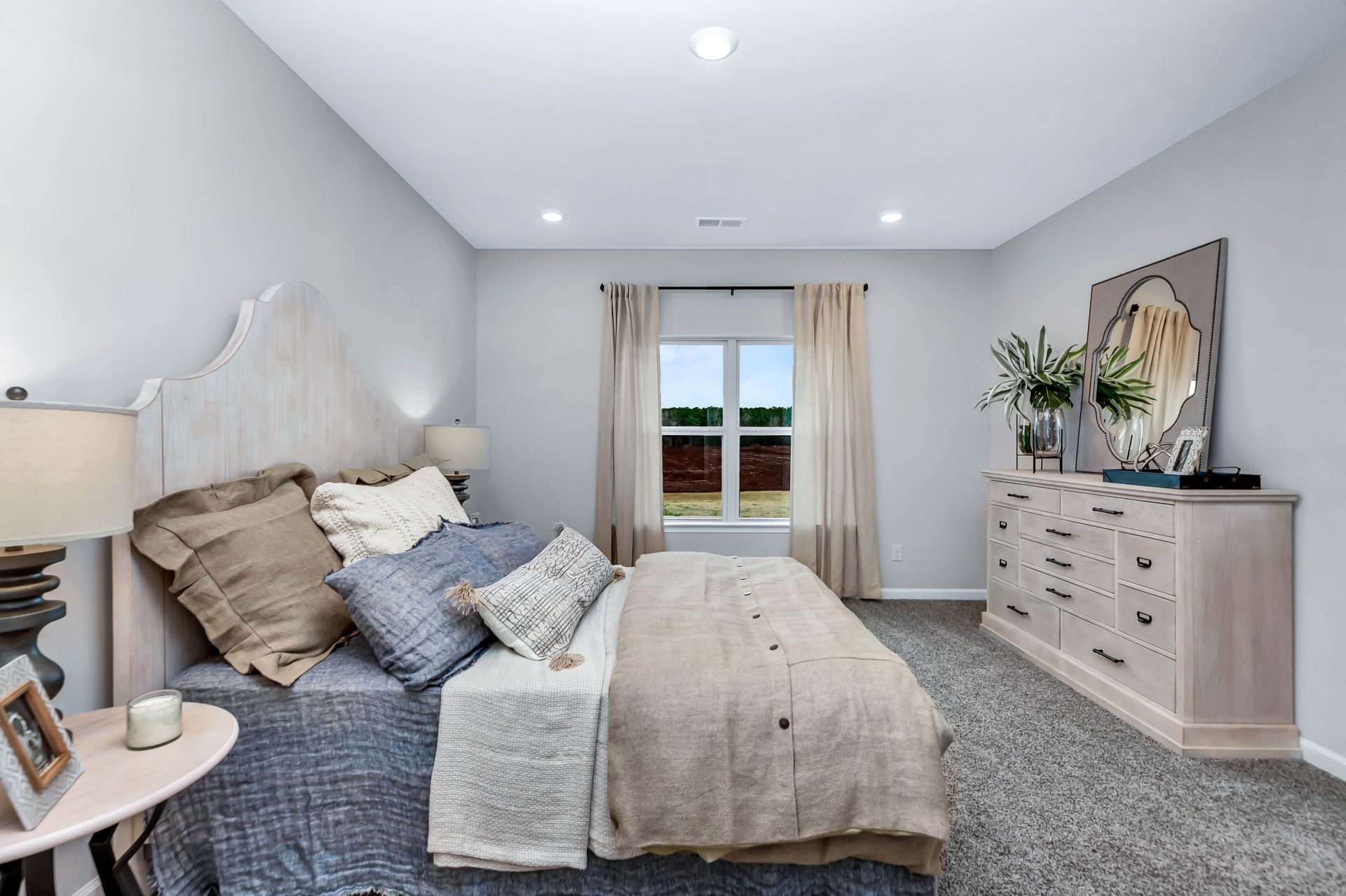 Bedroom with bed, dresser, and window, decorated in neutral tones.