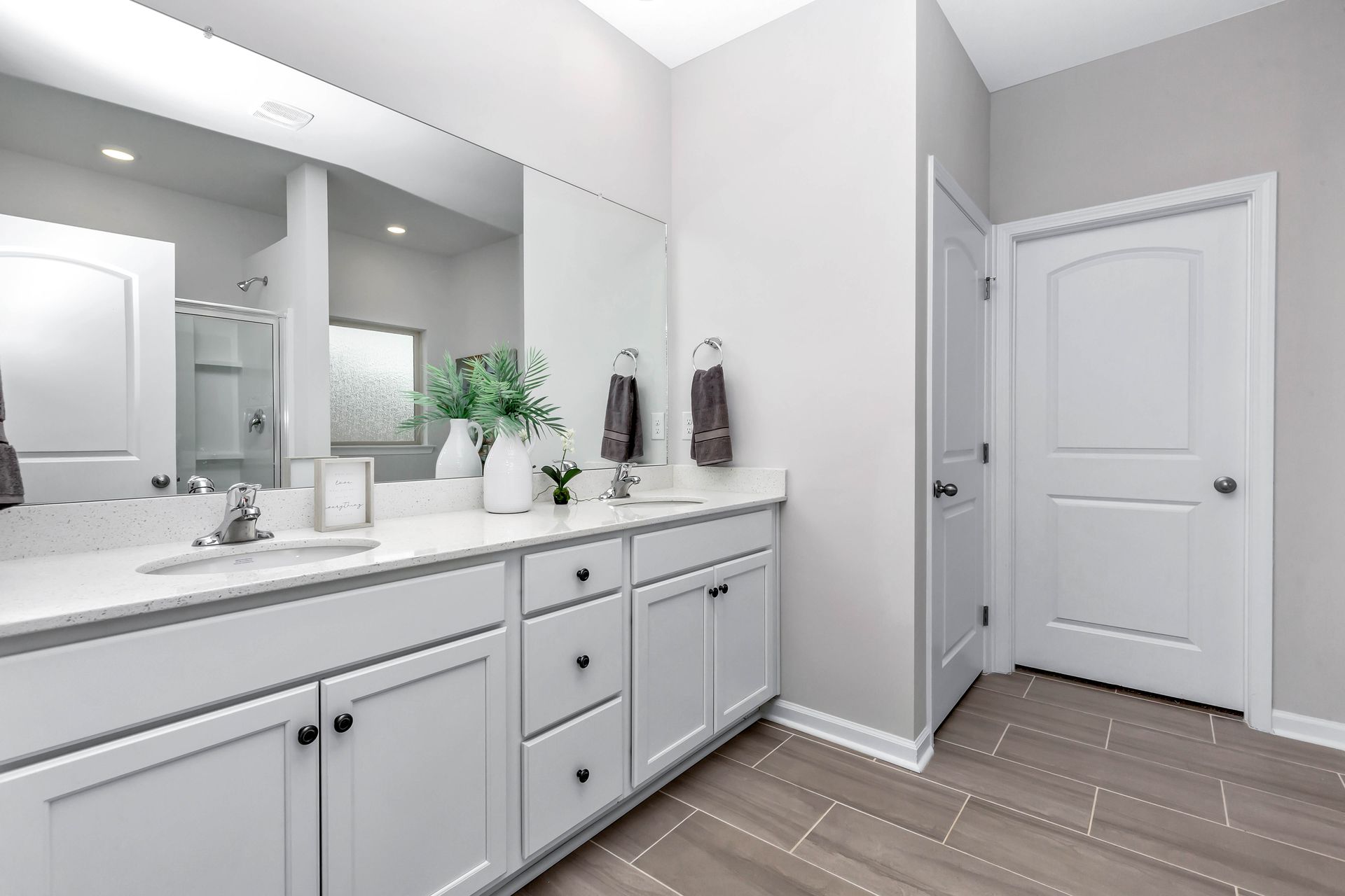 Modern bathroom with white cabinets, gray walls, and wood-look tile flooring.