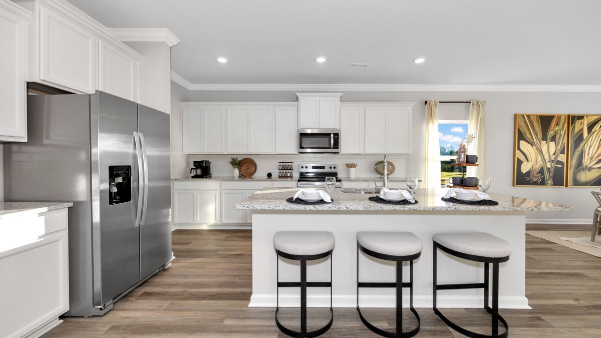 Modern kitchen with white cabinets, stainless steel appliances, and a breakfast bar with stools.