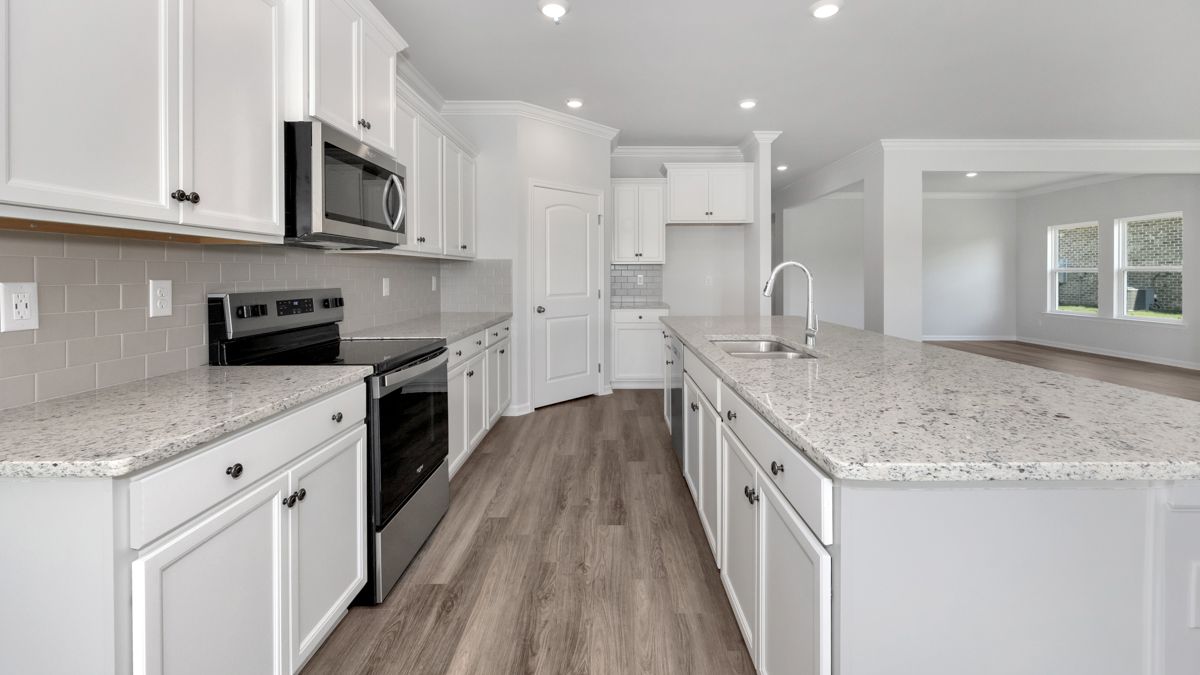 White kitchen with stainless steel appliances, light countertops, and hardwood floors.