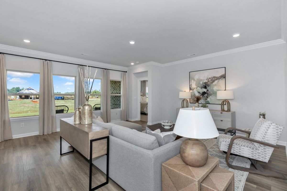 Living room with light wood floors, white walls, and large windows with outdoor view.