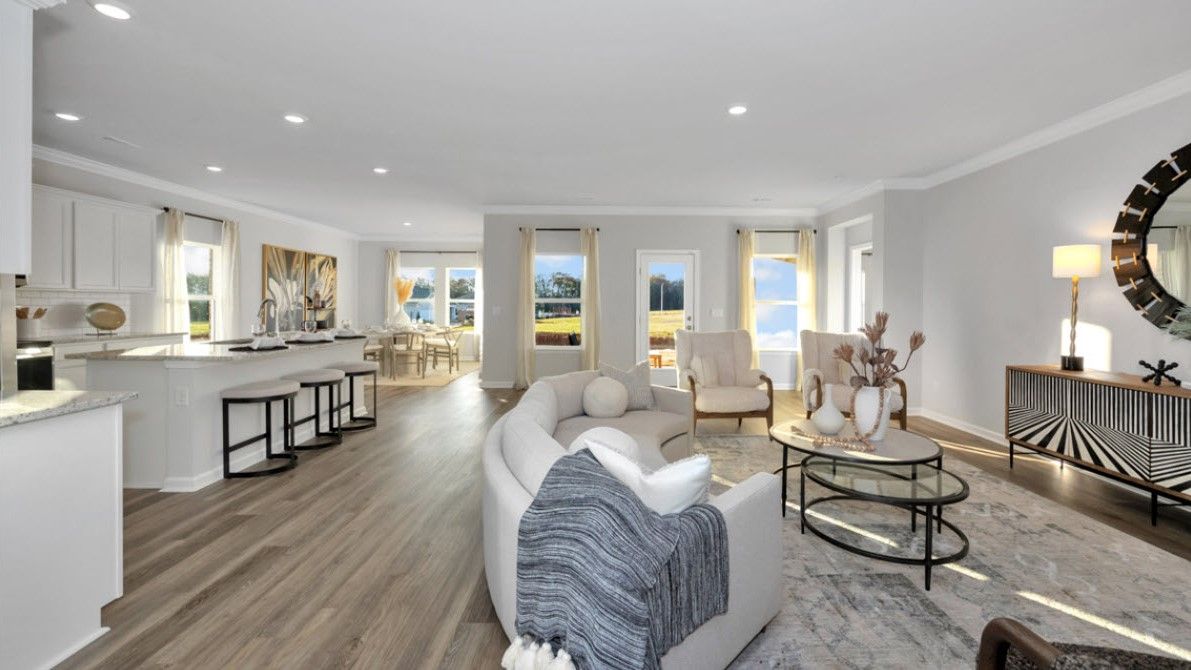 Open-concept living room with curved sofa, neutral tones, and dining area visible.