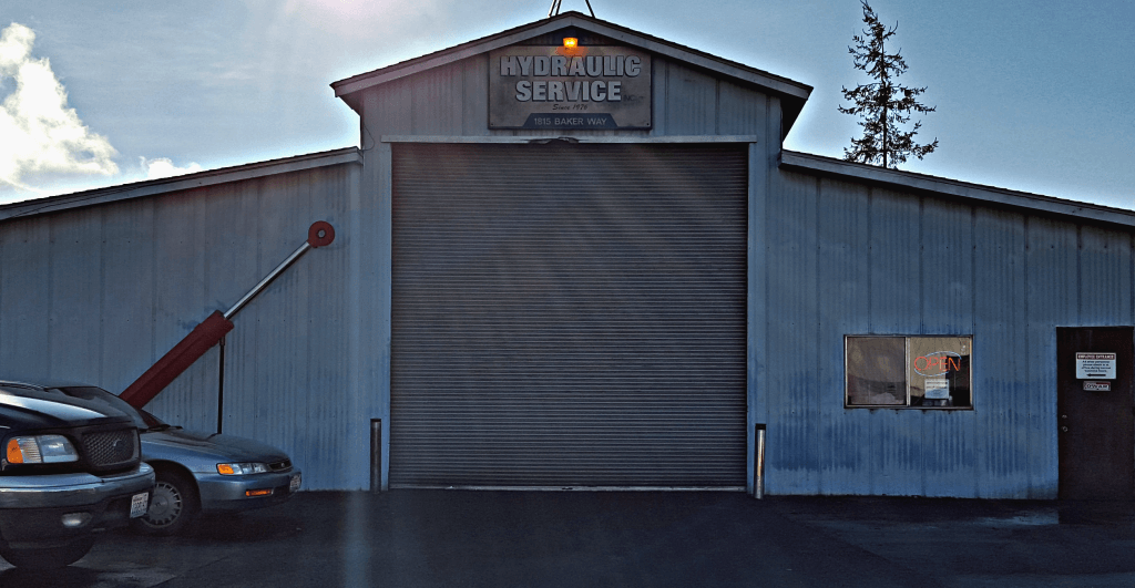 Hydraulic service shop with a large garage door. A red hydraulic arm is on the left.
