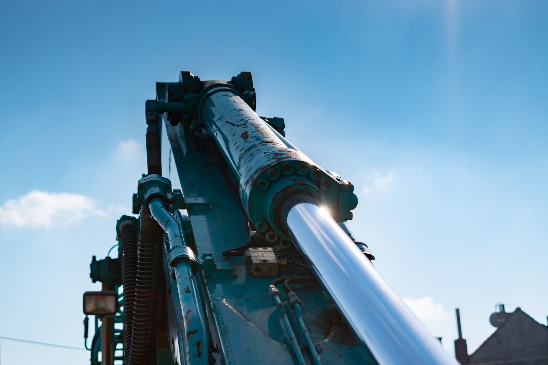 Industrial machine arm spraying bright blue water against a clear sky