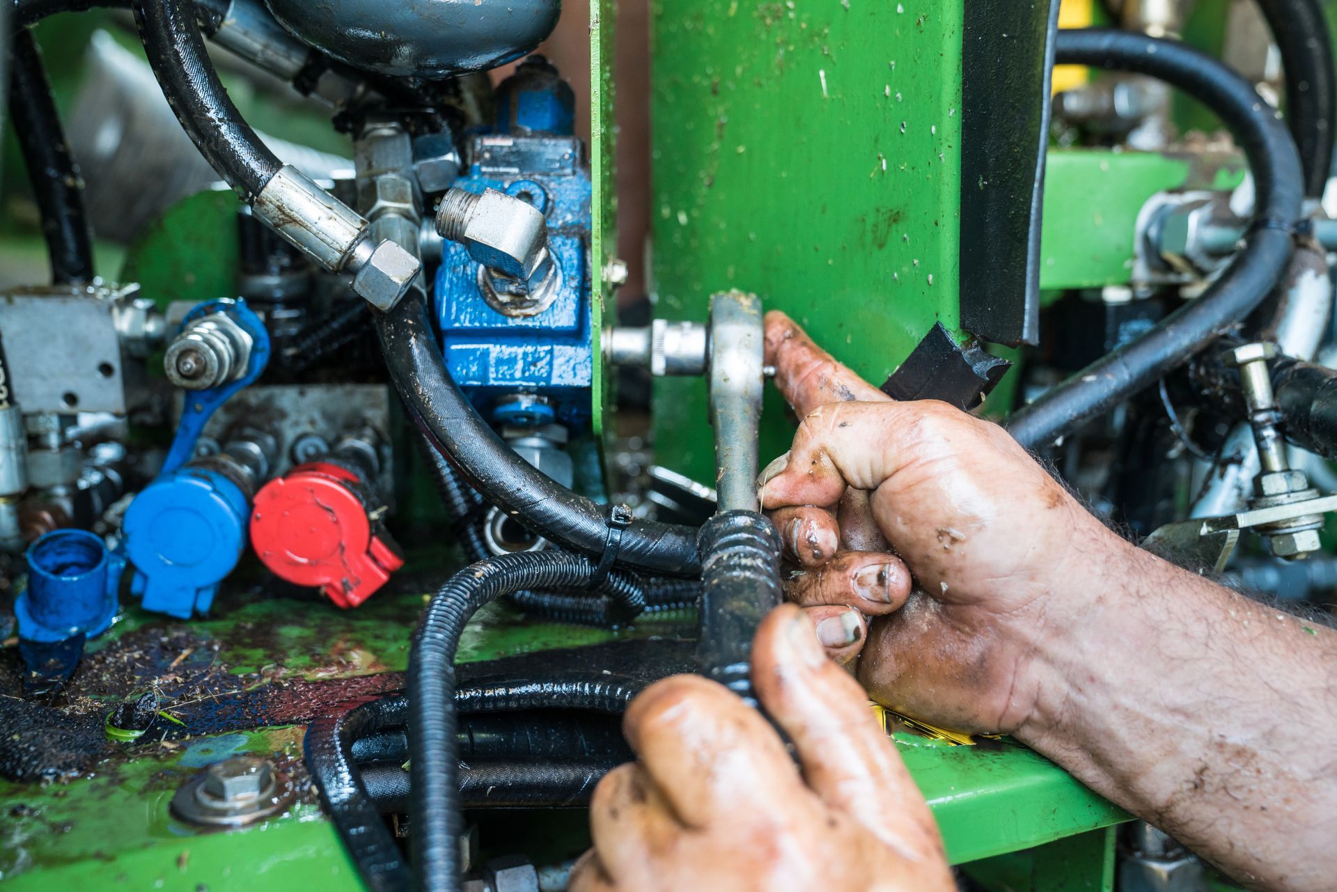 Close-up of a worker performing hydraulic repair service on industrial equipment.