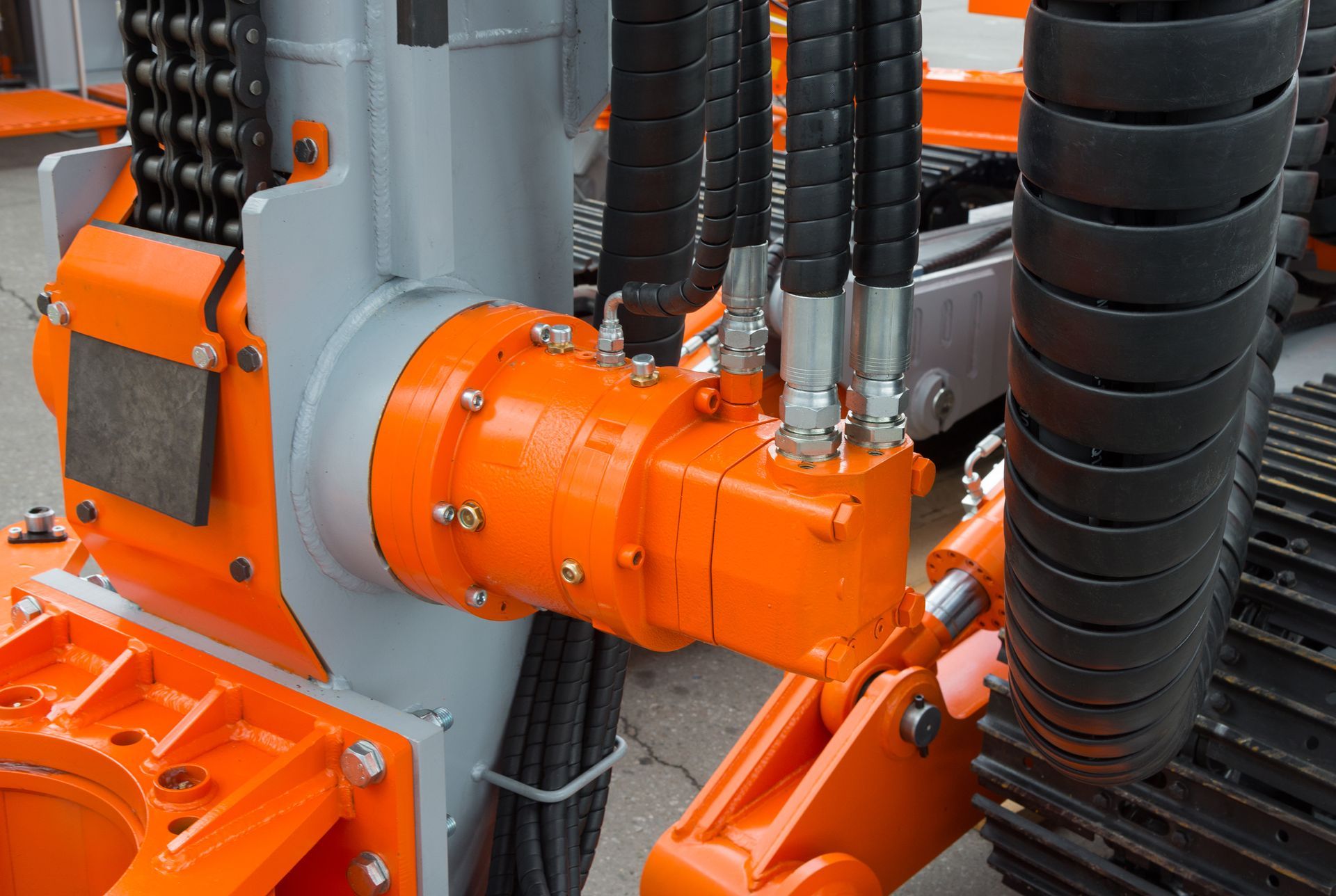 Orange and gray drilling rig components, including hydraulic hoses and a motor.
