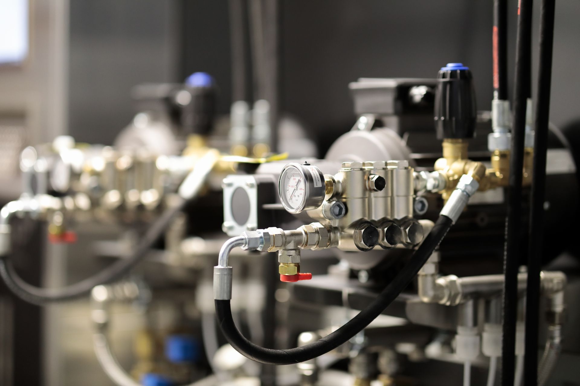 Close-up of industrial machinery with gauges, valves, and tubing; metallic colors.