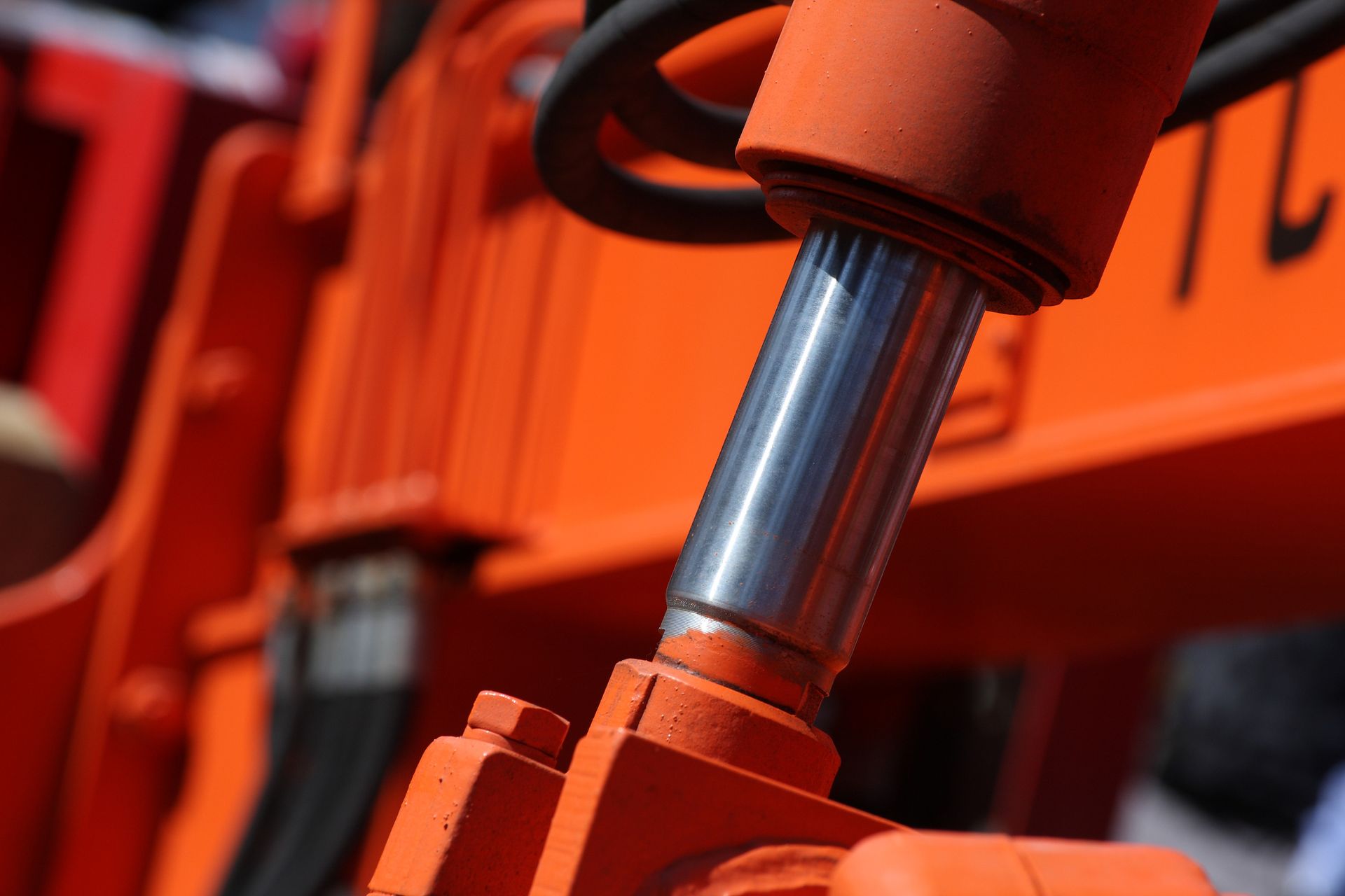 Orange hydraulic cylinder on heavy machinery.