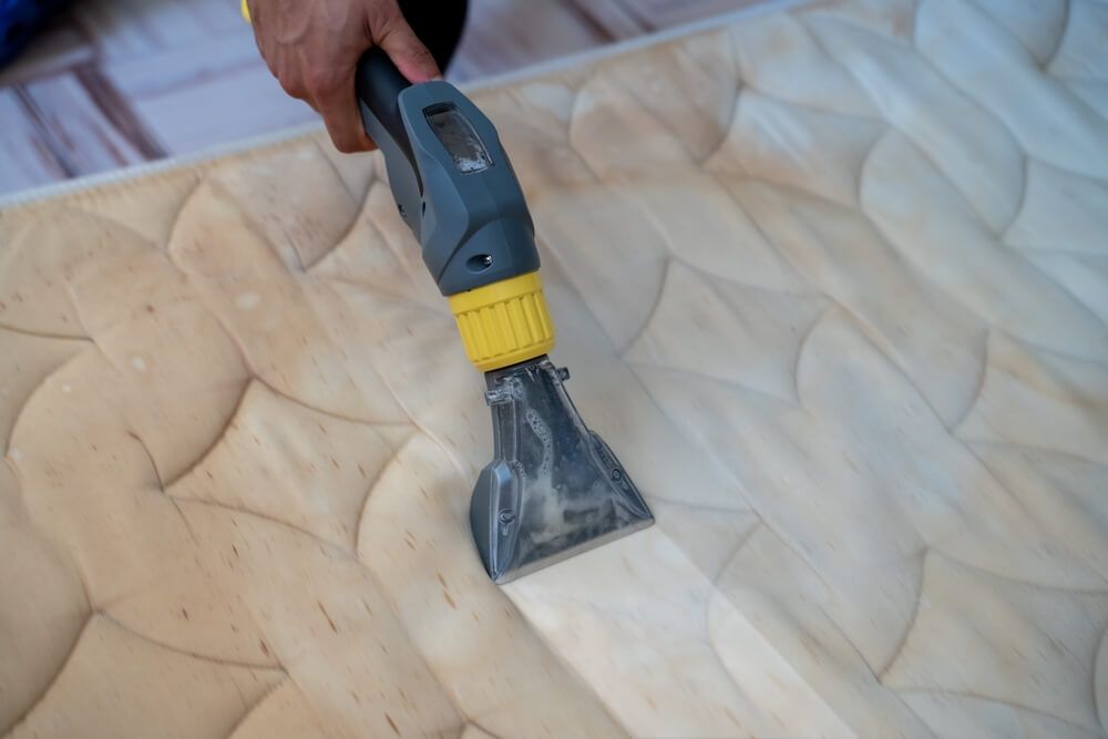 A Person is Cleaning a Mattress With a Vacuum Cleaner — On The Move Carpet Cleaning in Burleigh Waters, QLD
