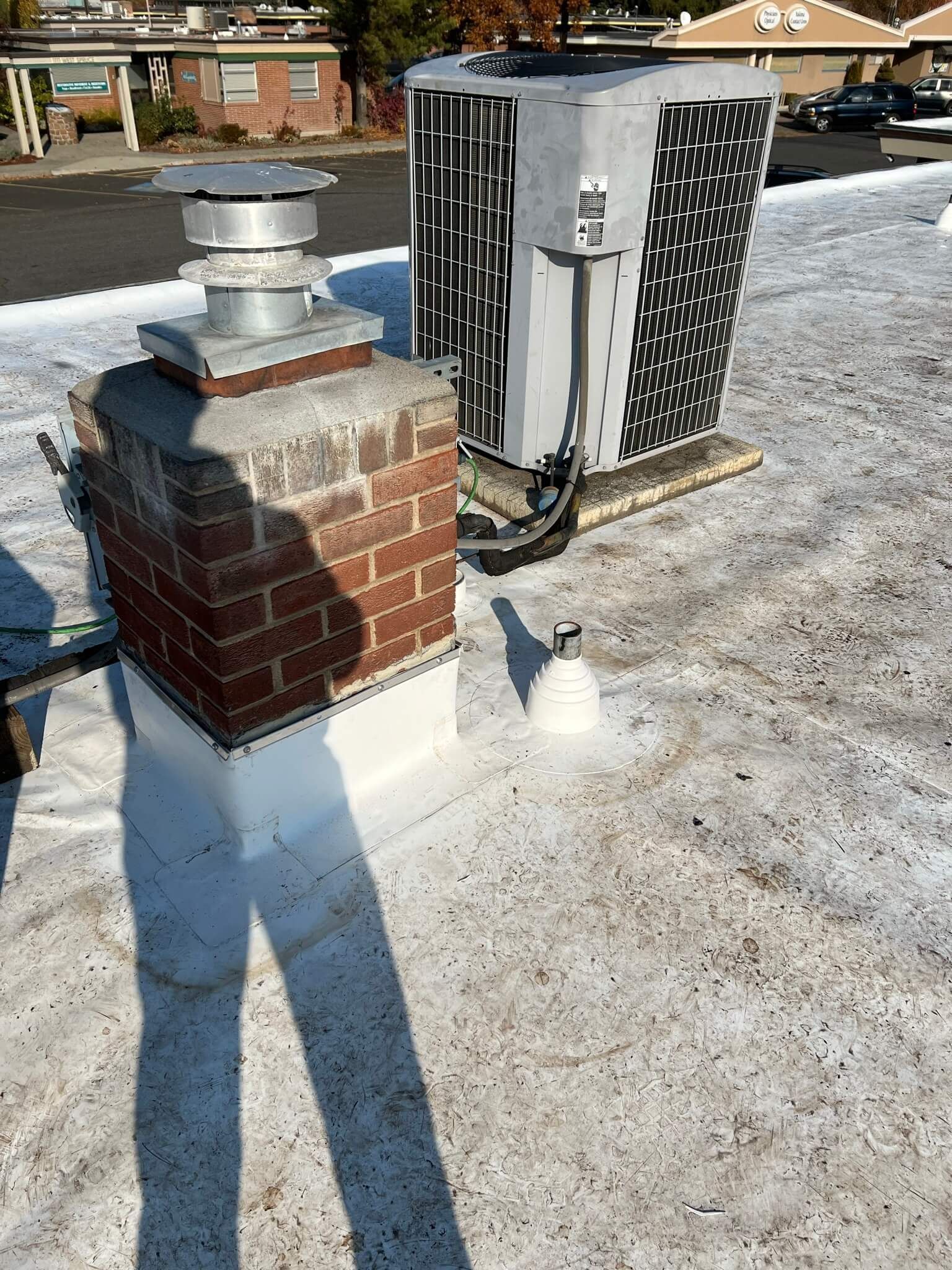 HVAC unit and brick chimney on the Labcorp roof during the preparation stage.
