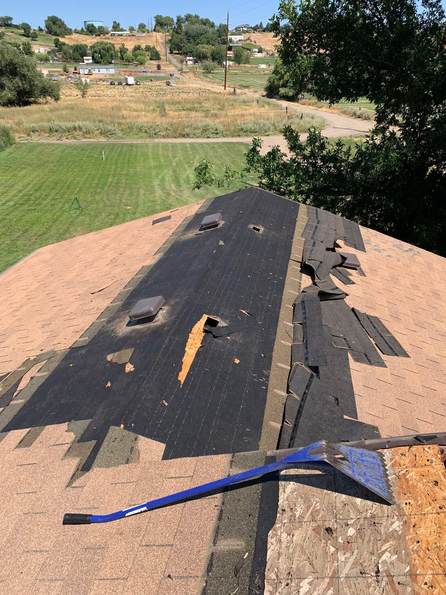 Roof tear-off in progress, showing partially removed shingles on a manufactured home.