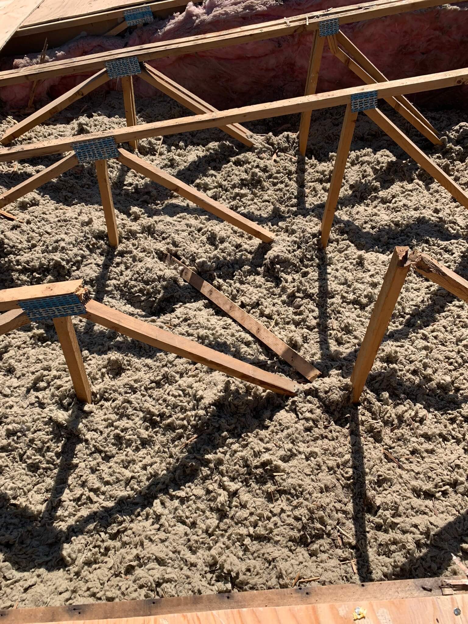 Close-up of damaged trusses with insulation in a manufactured home roof.