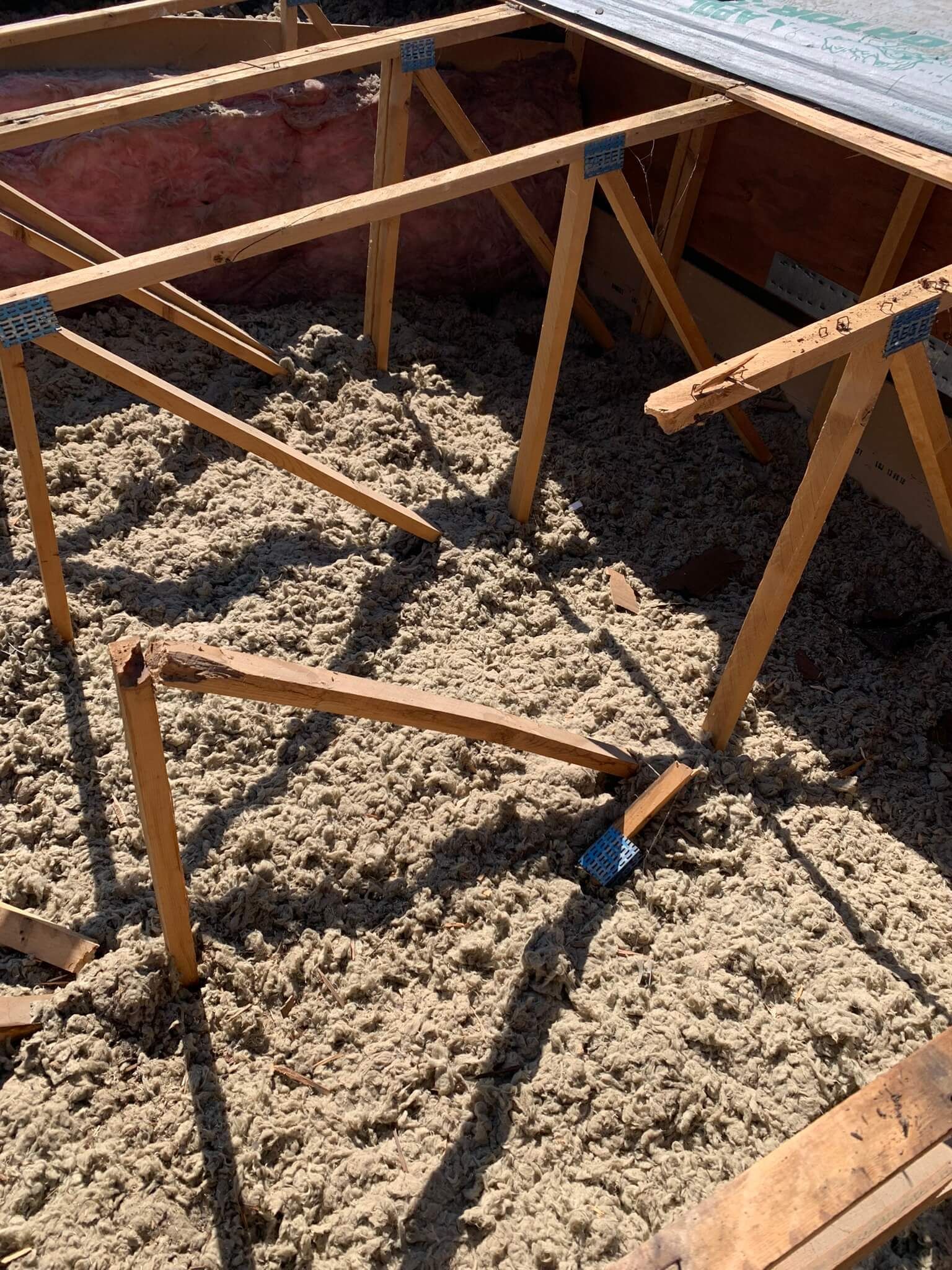 Reinforced roof trusses with new wood supports installed in a manufactured home roof.