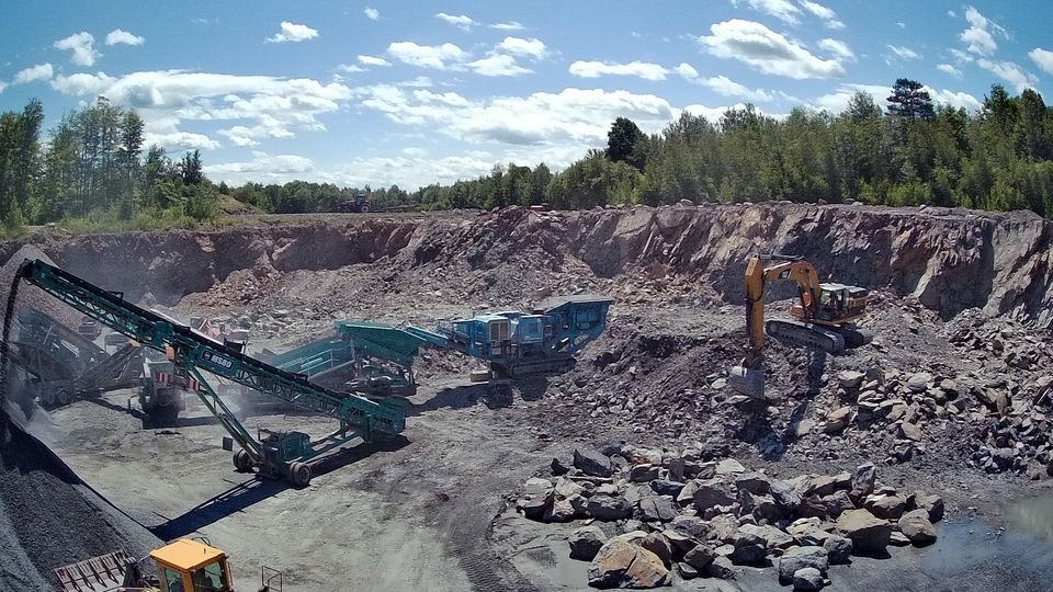 Un gros tas de roches est en cours de traitement dans une carrière.