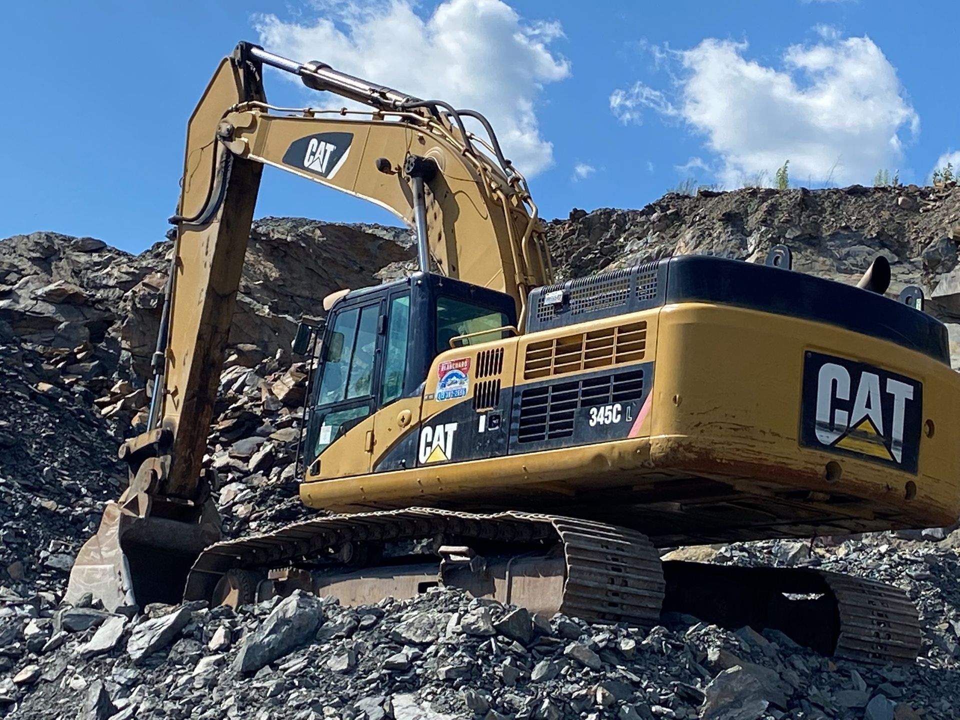 Une excavatrice à chat est assise sur un tas de rochers.