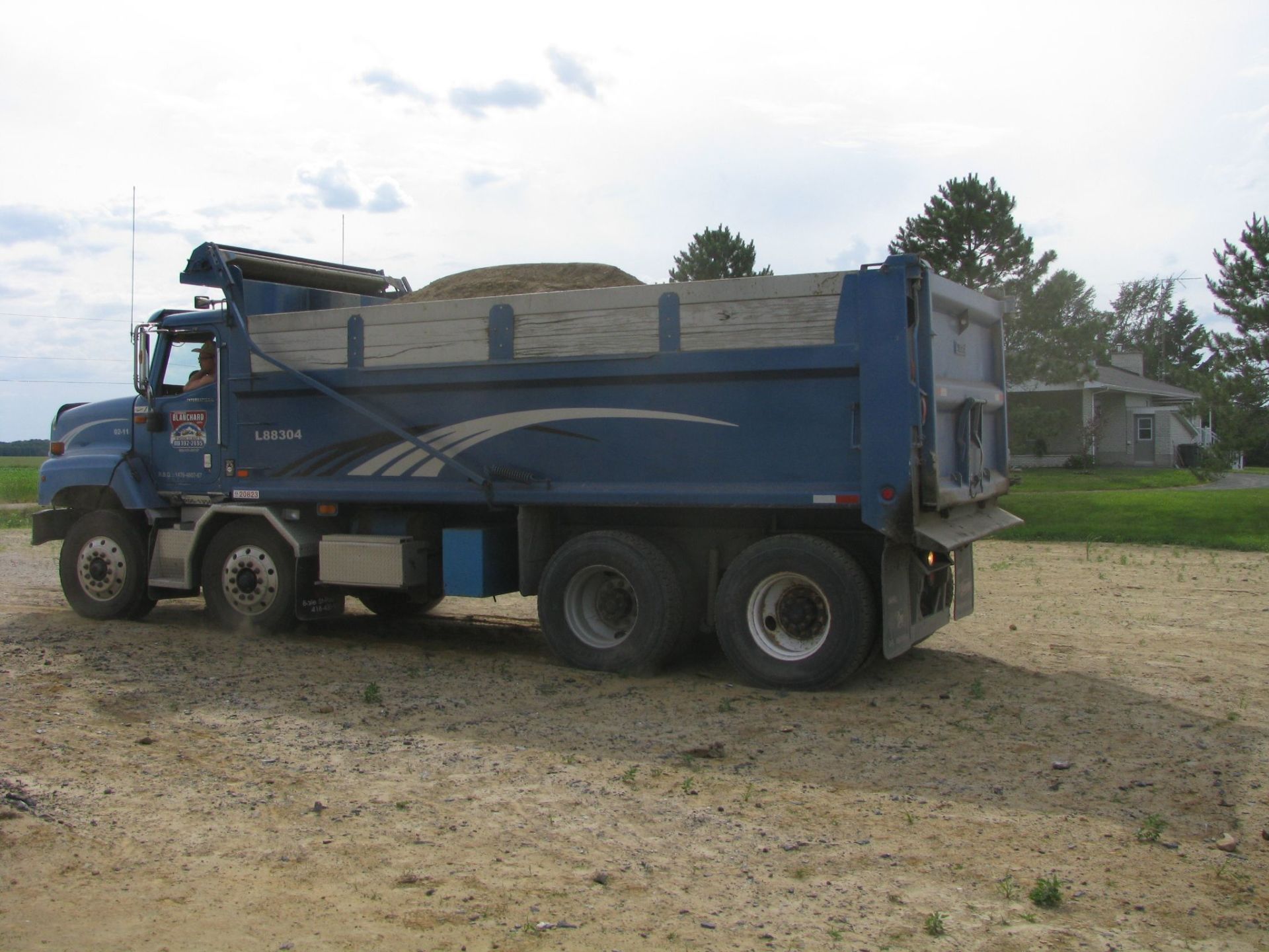 Un camion-benne bleu est garé sur un terrain en terre