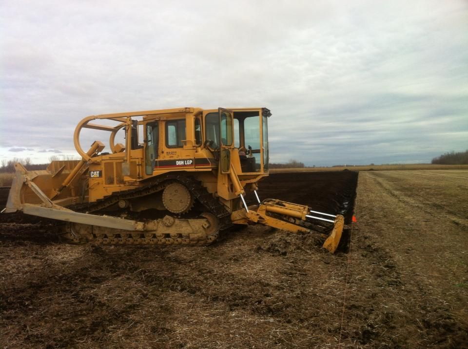 Un bulldozer est assis au milieu d'un champ de terre.